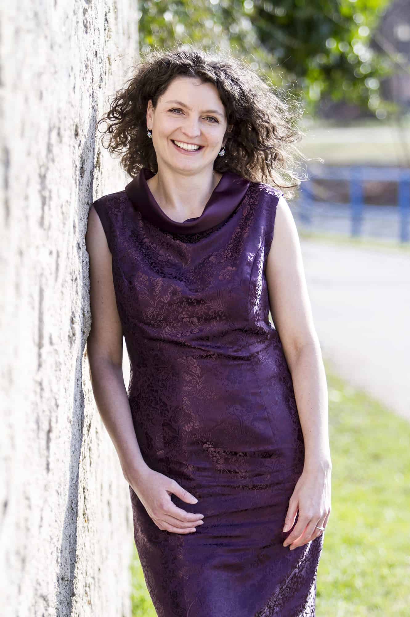 Marketa Huzel portrait in purple dress at the river and a wall