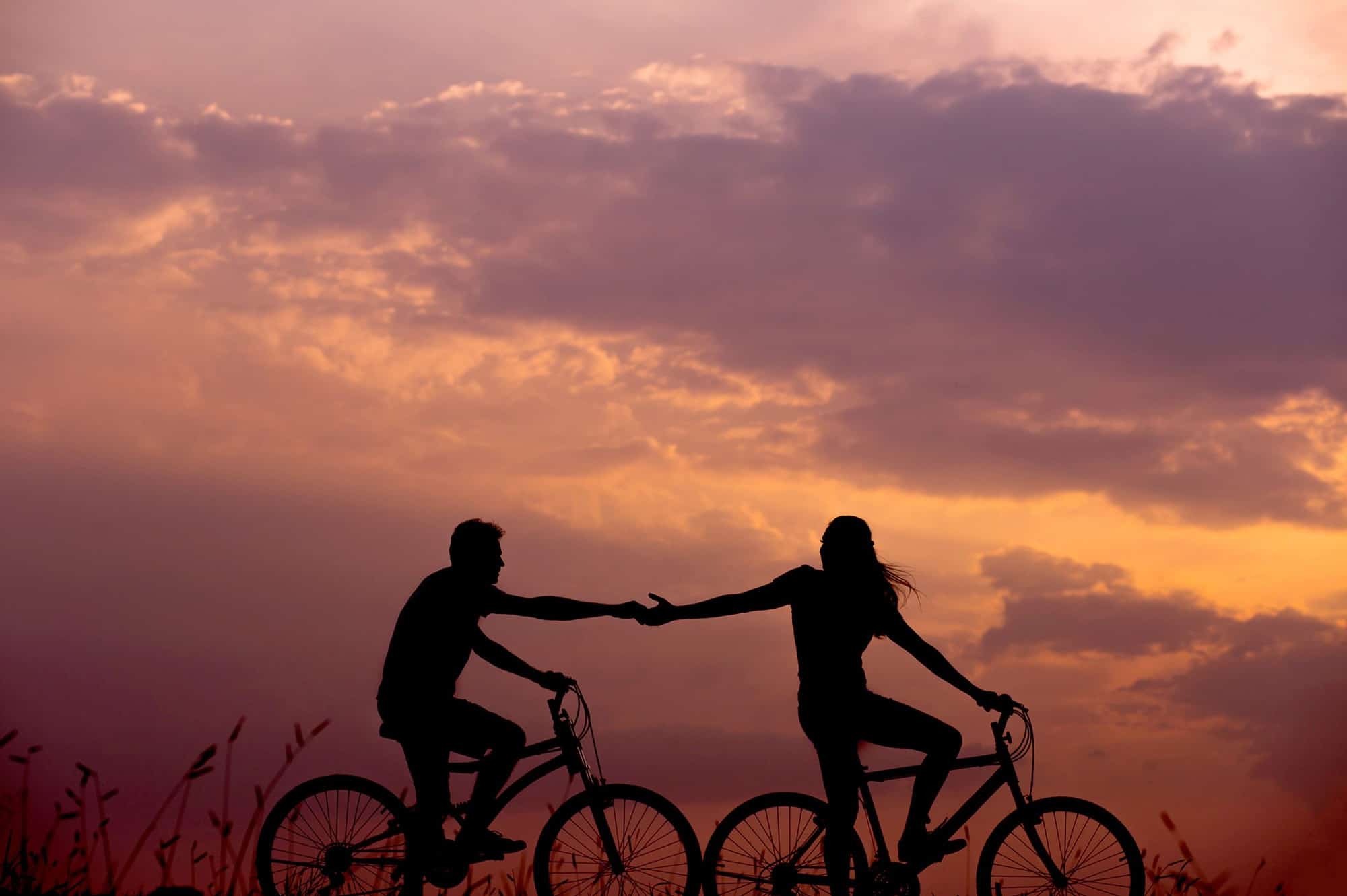 2 people riding bikes and holding hands