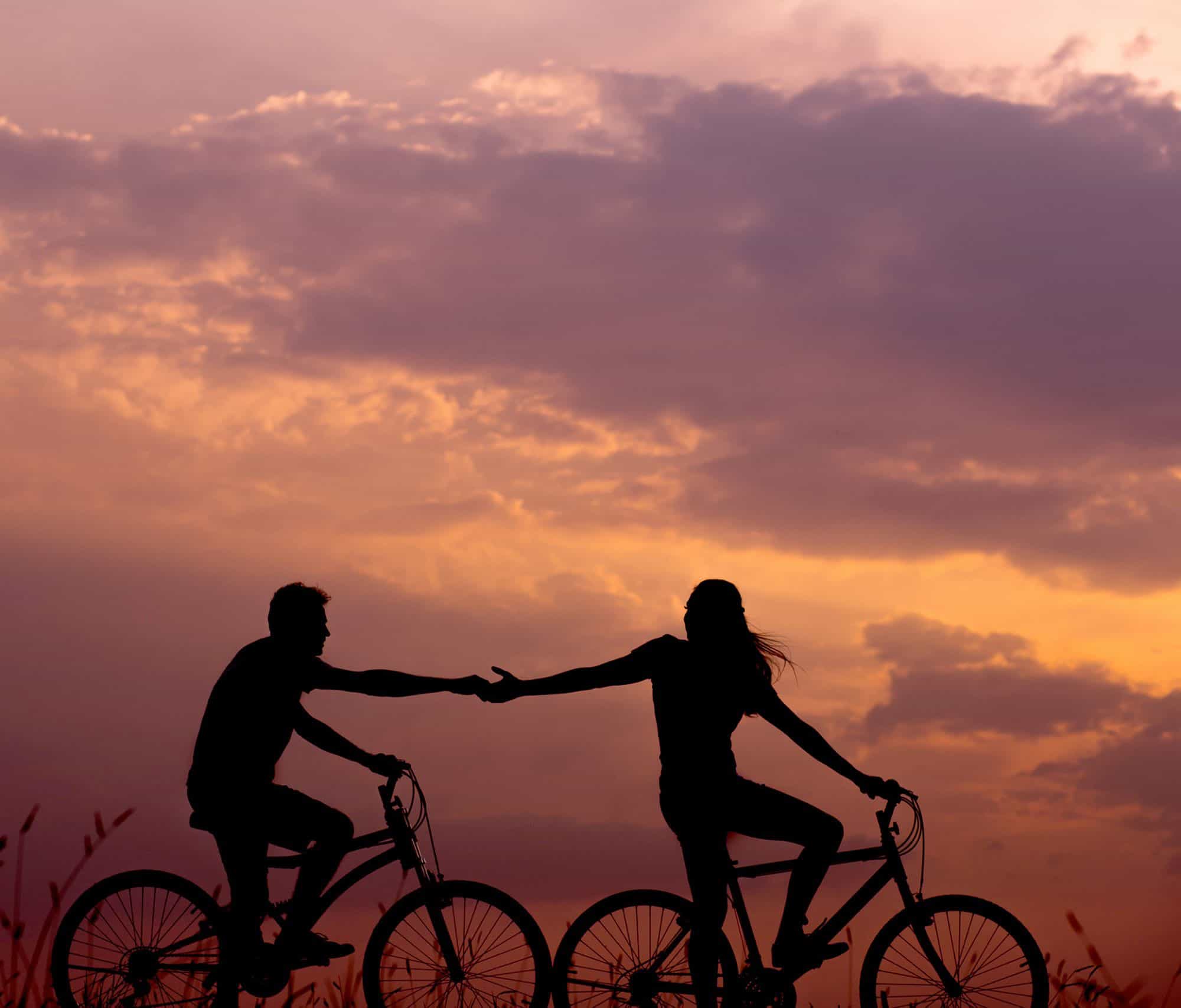 2 people riding bikes and holding hands