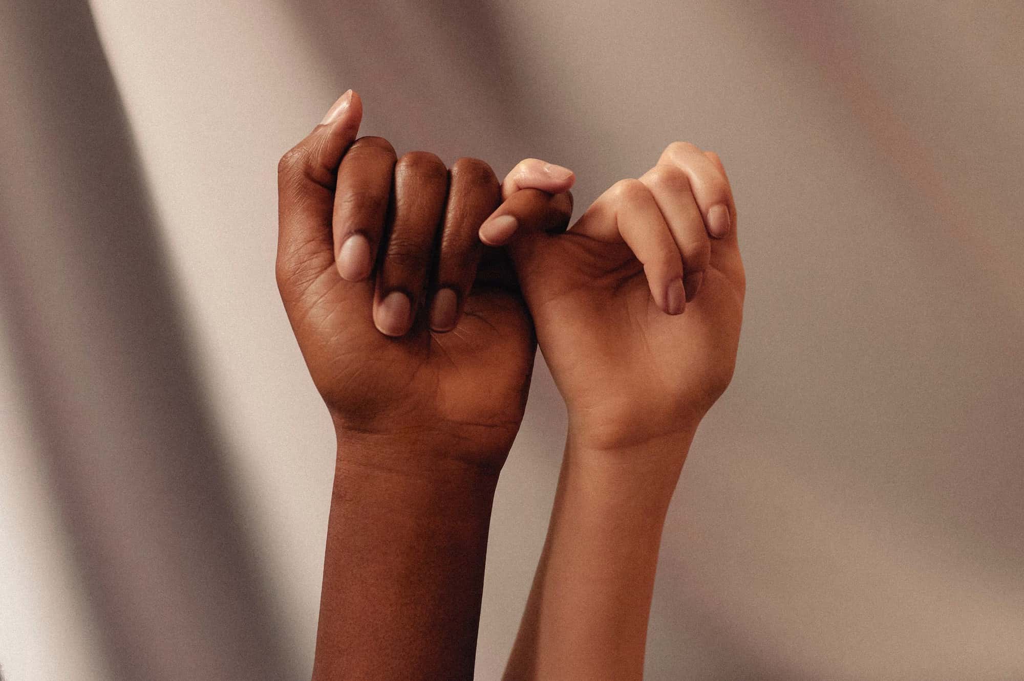 2 women hands, focus on holding pinkie fingers